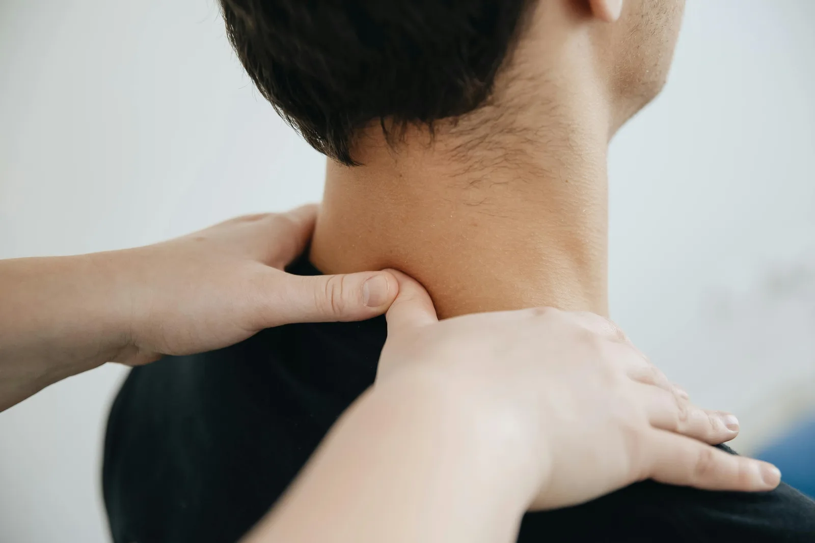 A remedial massage therapist applies trigger point pressure to a client's neck and upper shoulder during a session.